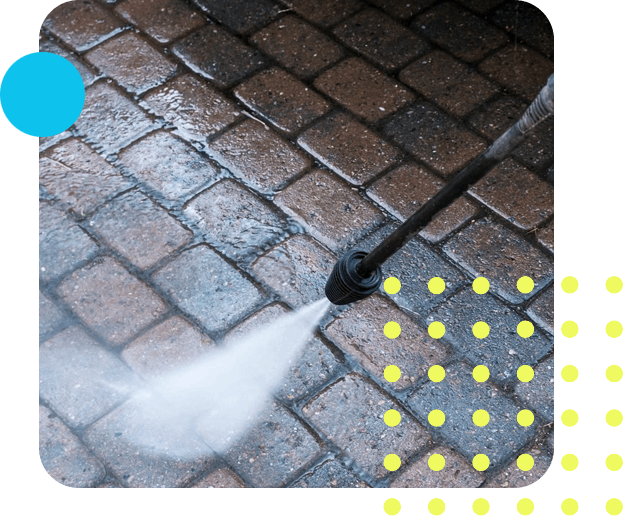 Pressure washer courtyard with paving stone. a hand holding the pressure washer with focus on the beam cleaning the stones at the courtyard.